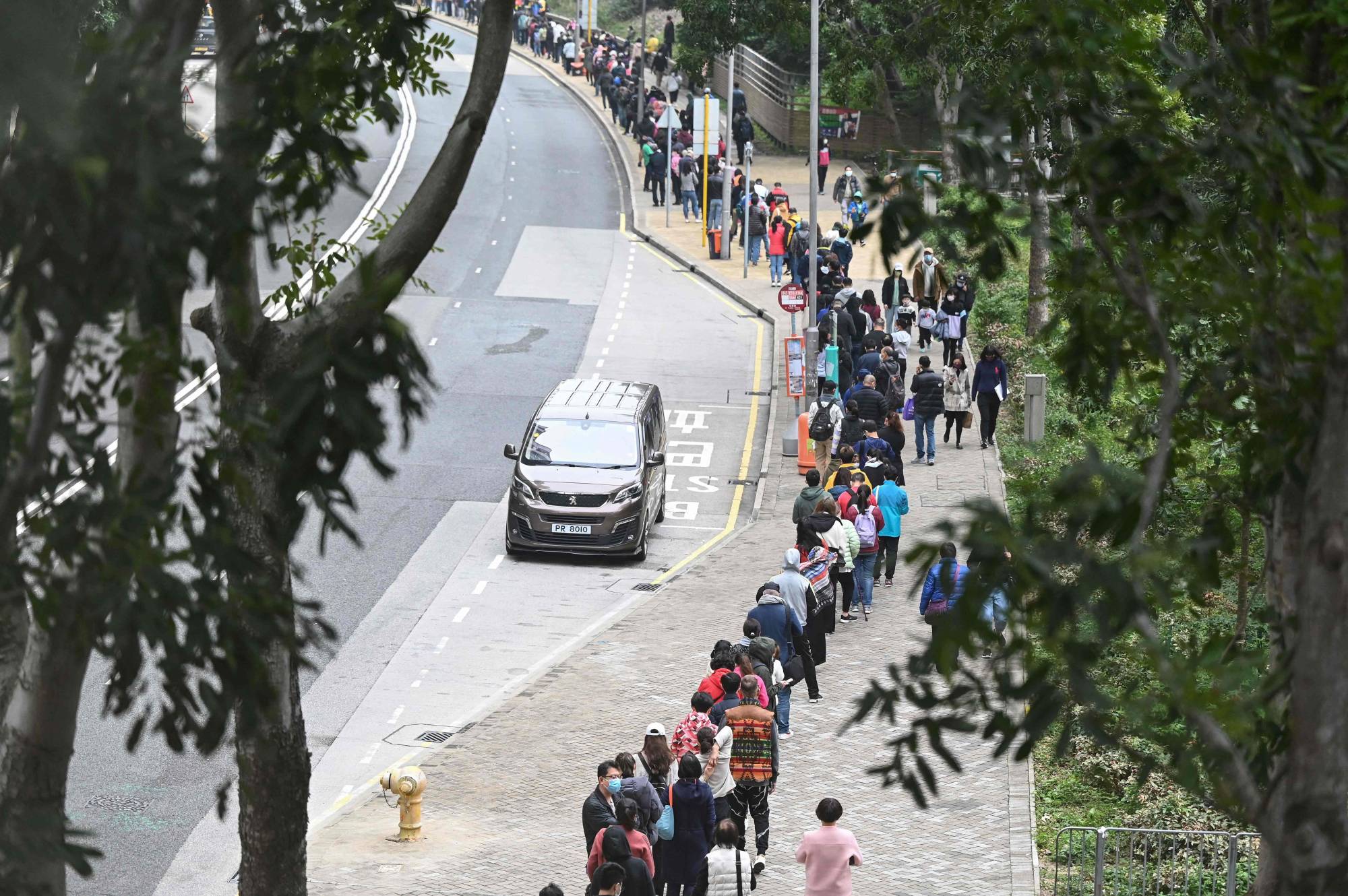 People queue at a mobile specimen collection station for COVID-19 testing in Hong Kong's Tung Chung district on Thursday as authorities scrambled to ramp up testing capacity following a record high number of new infections. | AFP-Jiji