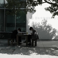 Two men sit outside a Nihon University building in the Jimbocho neighborhood of Tokyo in October 2020. There are worries that the entry ban could reinforce an inward-looking mentality among Japanese students. | BLOOMBERG