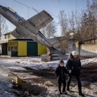 A woman walks underneath a military plane set as a monument to a former military base in a town on the outskirts of the Three Sisters border crossing, between Ukraine, Russia and Belarus, in Senkivka, Ukraine, on Monday. | GETTY IMAGES VIA BLOOMBERG