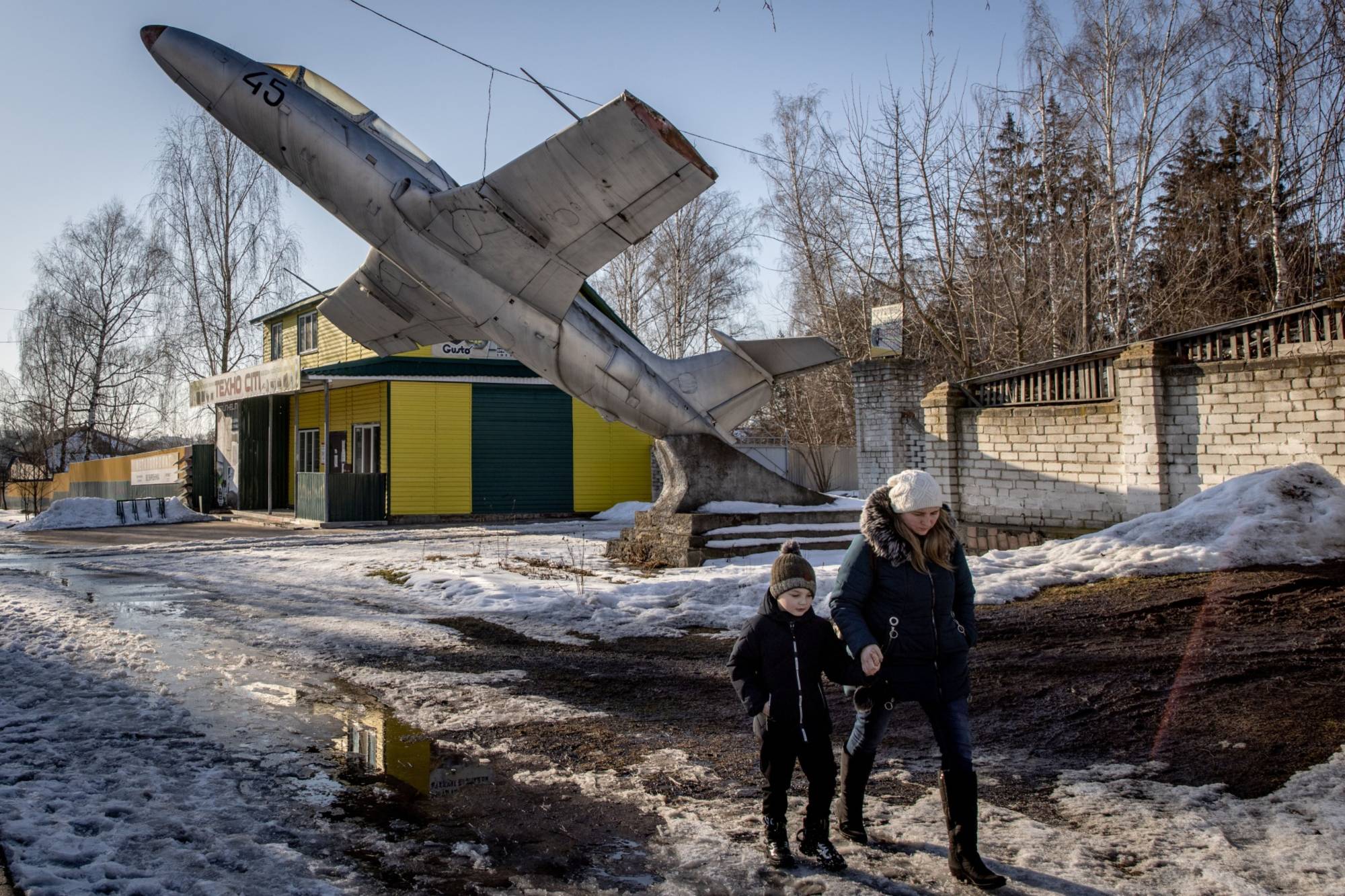 A woman walks underneath a military plane set as a monument to a former military base in a town on the outskirts of the Three Sisters border crossing, between Ukraine, Russia and Belarus, in Senkivka, Ukraine, on Monday. | Getty Images via Bloomberg