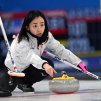 Satsuki Fujisawa curls the stone for Japan during their Olympic round-robin game against Great Britain in Beijing on Tuesday. | AFP-JIJI