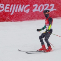 Benjamin Alexander of Jamaica slides into the judging area after his men\'s giant slalom run at the 2022 Beijing Winter Olympics on Sunday. | REUTERS