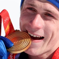 French skier Clement Noel bites his medal during the victory ceremony of the Beijing Olympics men\'s slalom event in Beijing on Wednesday. | REUTERS