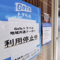 A sign outside a restaurant in Tokyo reads that it has suspended accepting coupons for the government\'s Go To Travel domestic tourism subsidy program. | KYODO