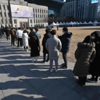 People wait in line to be tested for the COVID-19 coronavirus at a testing center in Seoul on Friday, after South Korea\'s daily COVID-19 caseload crossed 100,000 for the first time. | AFP-JIJI