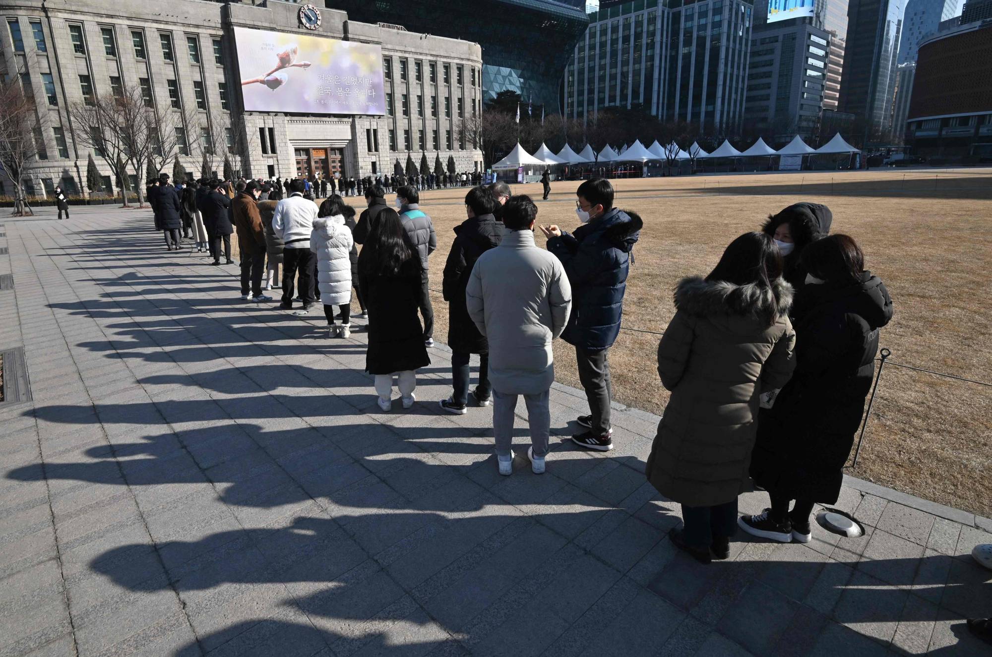 People wait in line to be tested for the COVID-19 coronavirus at a testing center in Seoul on Friday, after South Korea's daily COVID-19 caseload crossed 100,000 for the first time. | AFP-Jiji