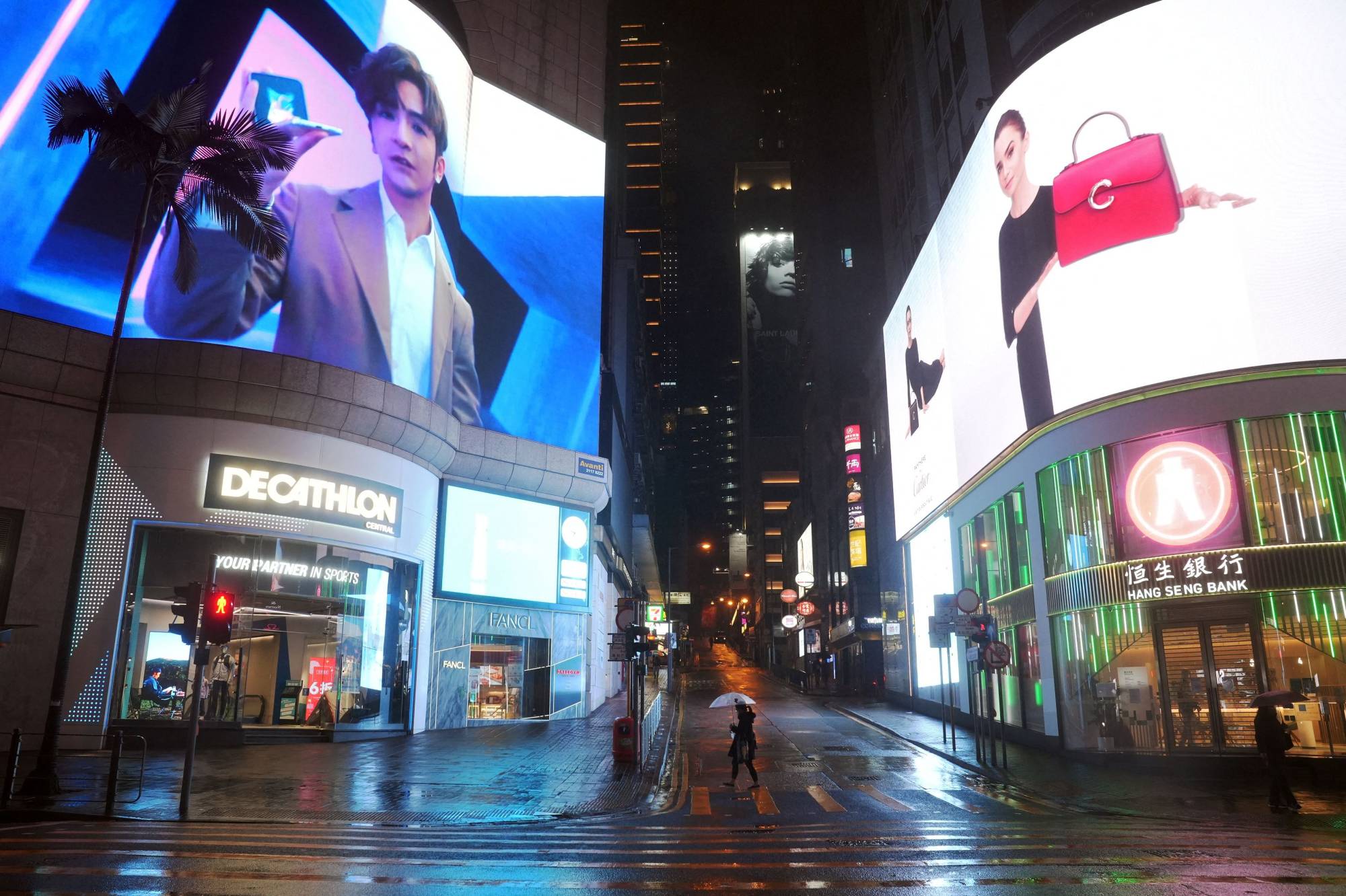 A pedestrian crosses a street in the shopping area of Hong Kong's Central district, following a surge in cases of COVID-19 in the territory on Sunday. | REUTERS