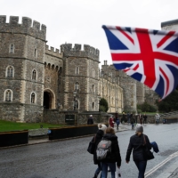 People gather outside Windsor Castle after it was announced that Queen Elizabeth tested positive for COVID-19 on Sunday. | REUTERS