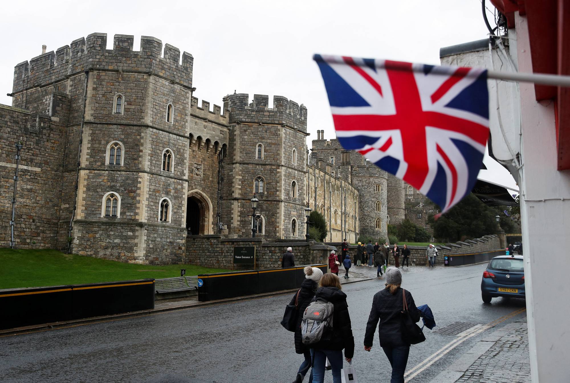 People gather outside Windsor Castle after it was announced that Queen Elizabeth tested positive for COVID-19 on Sunday. | REUTERS