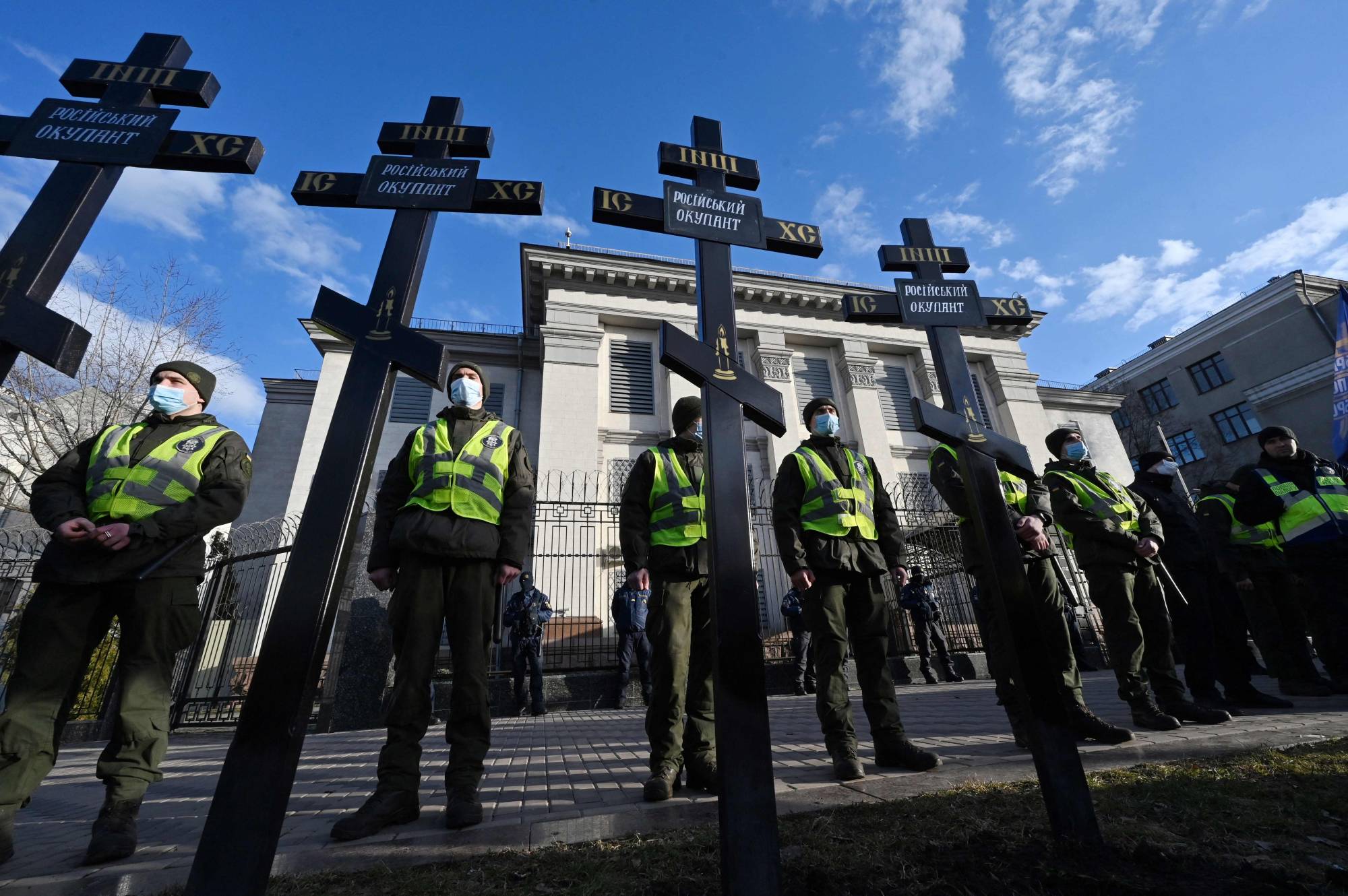Ukrainian security forces stand guard after activists set up symbolic tomb crosses with the inscription 'Russian occupiers' during a rally outside the Russian Embassy in Kyiv on Tuesday.   | AFP-JIJI