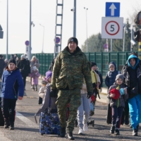 Ukrainians cross the border to Poland at the Korczowa-Krakovets crossing on Saturday following the Russian invasion of Ukraine. | AFP-JIJI