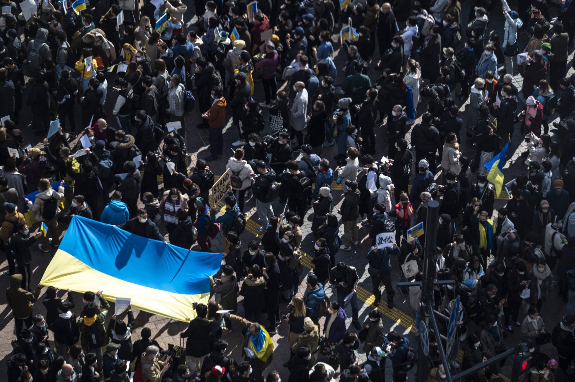 People hold the Ukrainian flag as they gather in Tokyo's Shibuya area to protest Russia's invasion of Ukraine, on Saturday. | AFP-JIJI