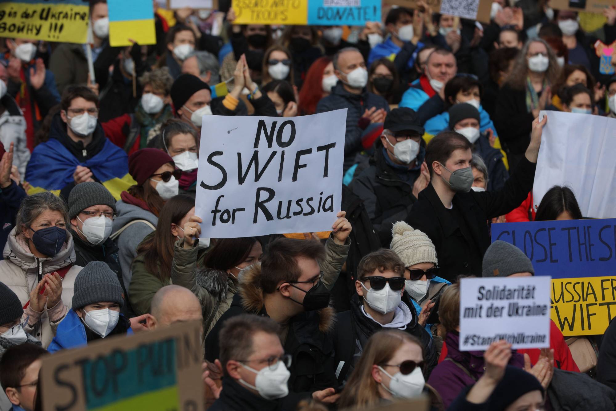 A protester holds a placard reading 'No SWIFT for Russia' during a rally against Russia's invasion of Ukraine, on Saturday in Frankfurt. | AFP-JIJI