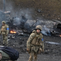 Ukrainian service members inspect the aftermath of a battle in the country\'s capital of Kyiv on Saturday. 

 | AFP-JIJI