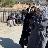 A member of the Taliban speaks with female students outside Kabul Education University on Saturday.  | REUTERS