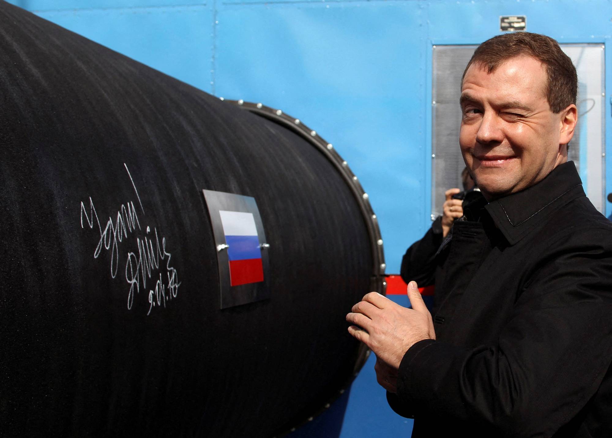Former Russian President Dmitry Medvedev gestures after writing 'Good Luck!' on a pipe of the Nord Stream pipeline near the Russian town of Vyborg in April 2010. | REUTERS