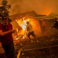 A firefighter and local residents rush to a burning house in an attempt to extinguish forest fires that are approaching the village of Pefki on Evia island, Greece, in August 2021 | AFP-JIJI