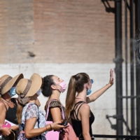 A group of women cool off in front of a fan during a heat wave in August 2021 as they queue at the entrance of The Colosseum in Rome. | AFP-JIJI