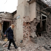 A local resident walks past a house that was damaged by shelling in the separatist-controlled city of Donetsk, Ukraine, on Monday. |  REUTERS