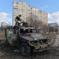 A Ukrainian Territorial Defense fighter examines a destroyed Russian military vehicle in Kharkiv, Ukraine, on Sunday. | AFP-JIJI