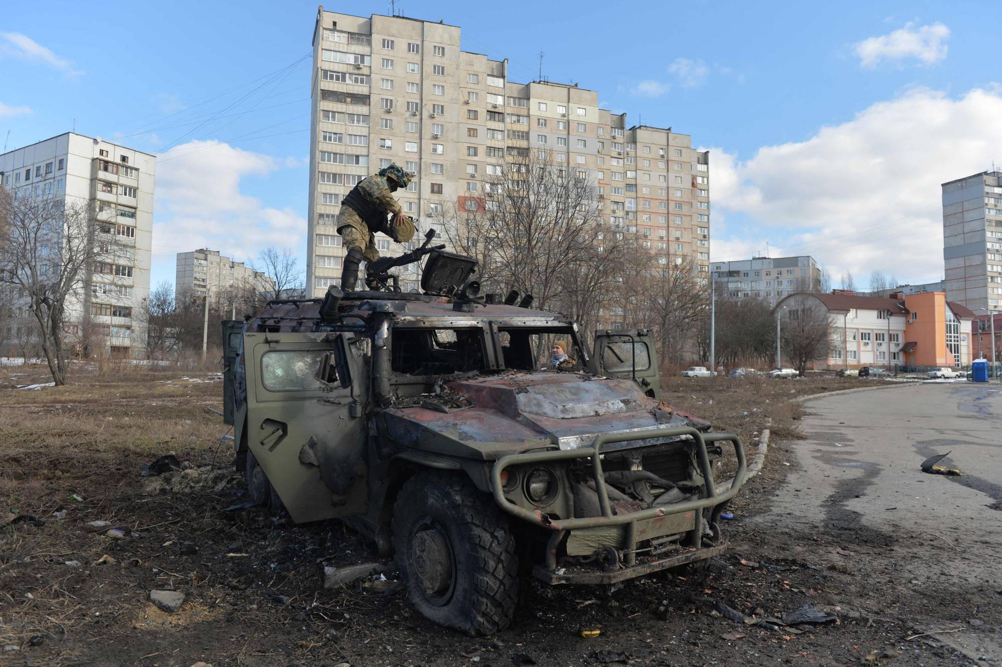 A Ukrainian Territorial Defense fighter examines a destroyed Russian military vehicle in Kharkiv, Ukraine, on Sunday. | AFP-JIJI