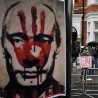 Demonstrators hold protest placards, with a depiction of Russian President Vladimir Putin seen in front, opposite the Russian Embassy in London, on Tuesday. | REUTERS