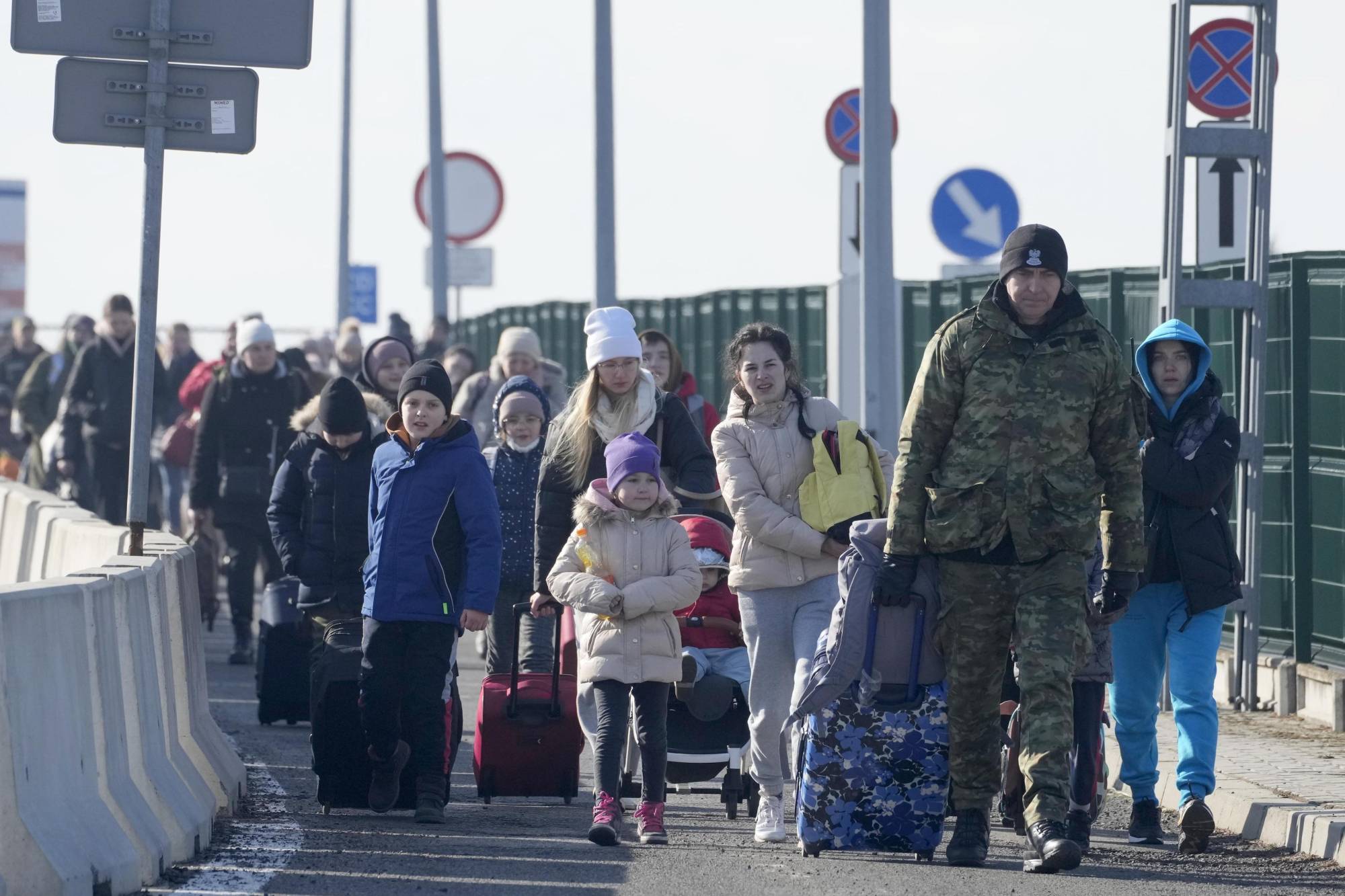 A Polish border guard assists refugees from Ukraine at the Korczowa border crossing on Saturday. | AP / VIA KYODO