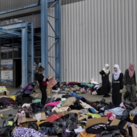 People go through clothing at a makeshift reception center for refugees at a shopping mall in Radymno, Poland, on Thursday. | MACIEK NABRDALIK / THE NEW YORK TIMES