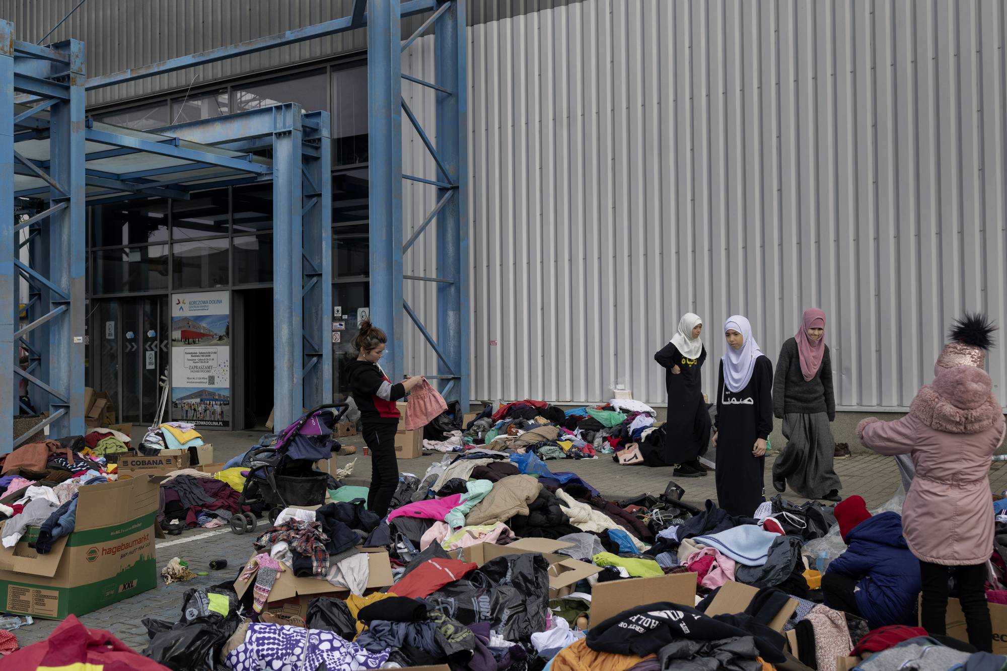 People go through clothing at a makeshift reception center for refugees at a shopping mall in Radymno, Poland, on Thursday. | Maciek Nabrdalik / The New York Times