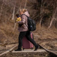 A refugee woman and dog from Ukraine cross the Polish-Slovakian border at Kroscienko, Poland, on Thursday. | AFP-JIJI