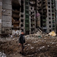 A man stands in front of a residential building damaged in shelling in the city of Chernihiv, Ukraine, on Friday. | AFP-JIJI