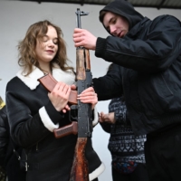 A woman learns how to use an AK-47 assault rifle during a self-defense course for civilians on the outskirts of Lviv, Ukraine, on Friday. | AFP-JIJI