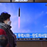 A TV screen shows a news broadcast with file footage of a North Korean missile test, at the main railway station in Seoul on Saturday. | AFP-JIJI
