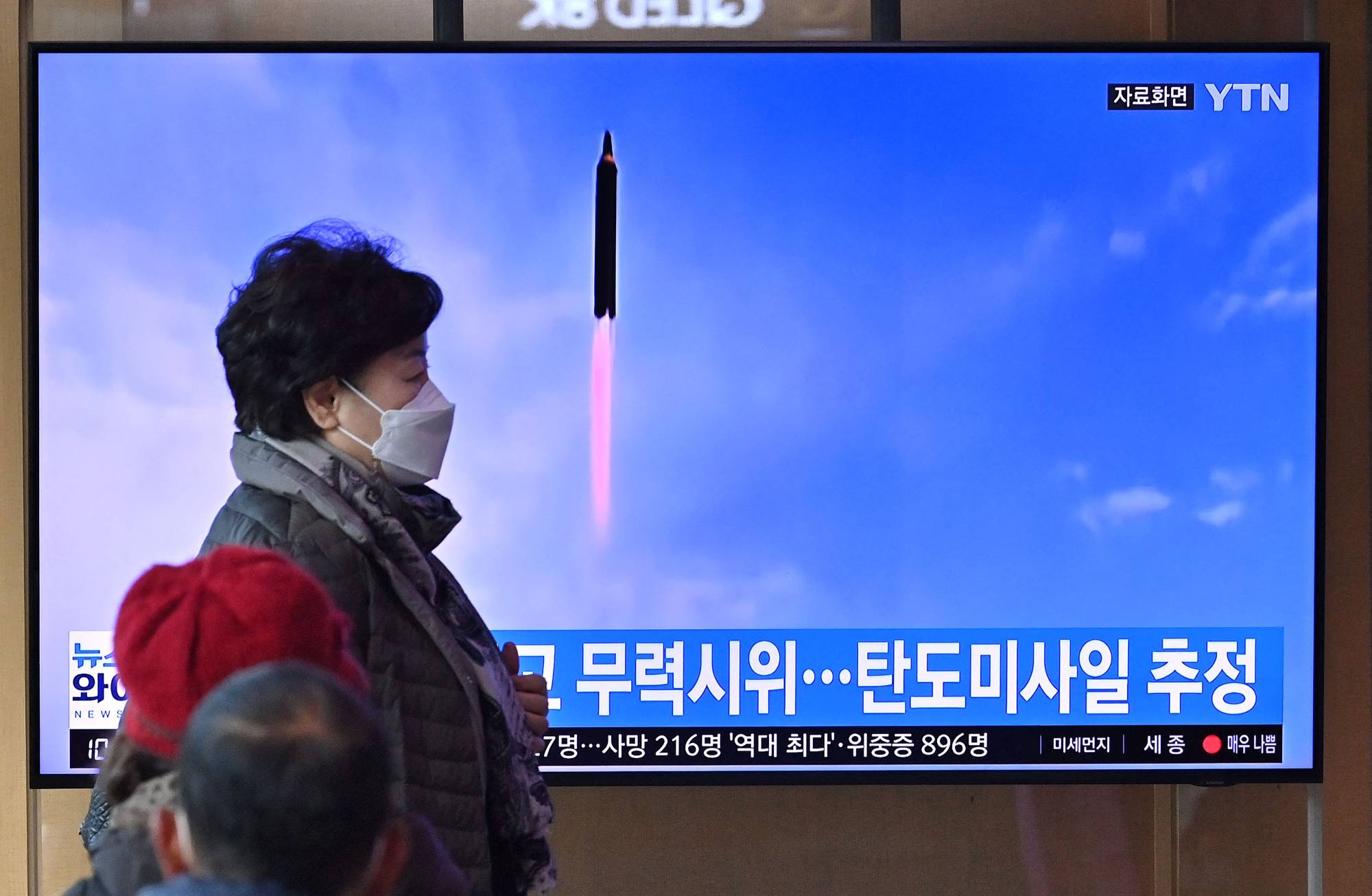 A TV screen shows a news broadcast with file footage of a North Korean missile test, at the main railway station in Seoul on Saturday. | AFP-JIJI