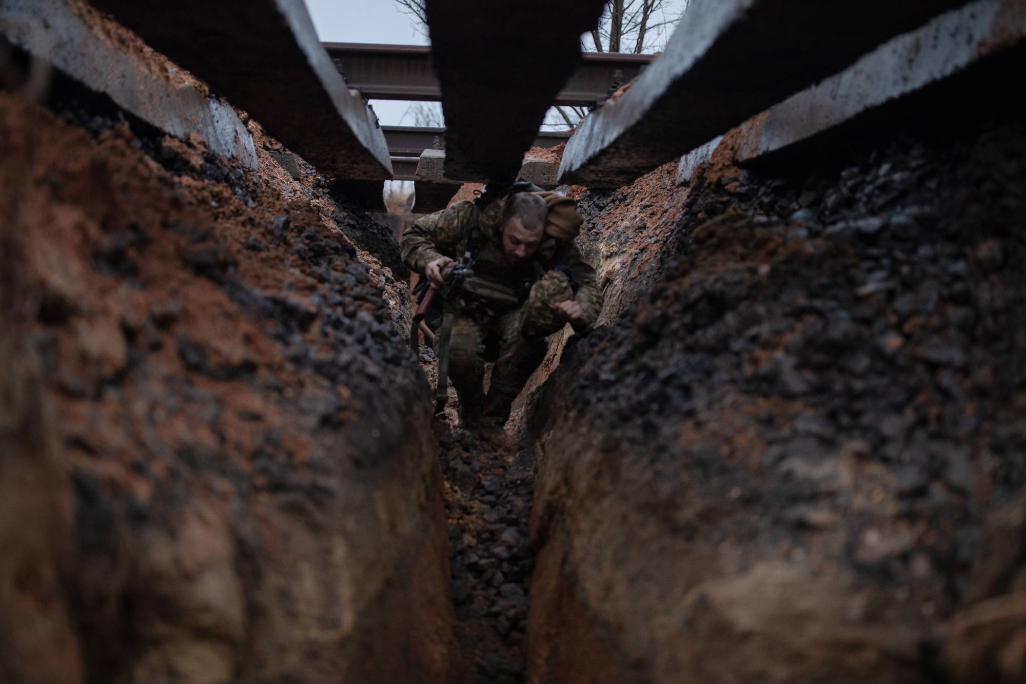 A Ukrainian Marine moves along a trench below railroad tracks in Verkhnotoretske, Ukraine, on Feb. 8. | Tyler Hicks / The New York Times