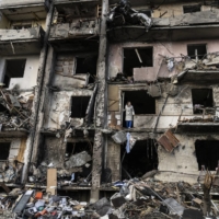 Ukrainians clean up debris after a residential building was hit by missiles in Kyiv on Feb. 25.  | LYNSEY ADDARIO / THE NEW YORK TIMES