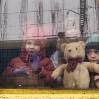 Ukrainian children ride an evacuation train through Kyiv as it travels west toward Lviv, Ukraine, on Thursday.  | LYNSEY ADDARIO / THE NEW YORK TIMES