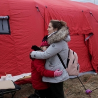 A woman hugs a child as they wait for transport after fleeing the Russian invasion of Ukraine, at a border crossing in Vysne Nemecke, Slovakia, on Saturday. | REUTERS