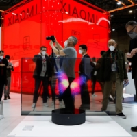People look at a Xiaomi glass screen during the 2022 Mobile World Congress (MWC) in Barcelona on  Tuesday. | REUTERS