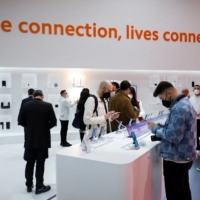 People look at devices at the Xiaomi exhibit at the 2022 Mobile World Congress (MWC) in Barcelona on Tuesday. | REUTERS