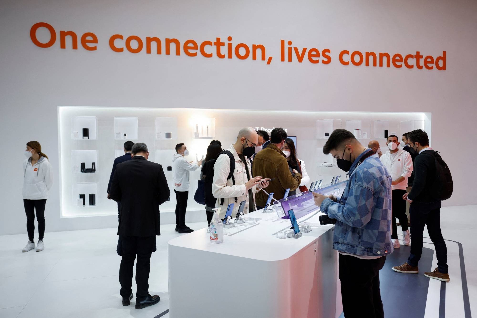 People look at devices at the Xiaomi exhibit at the 2022 Mobile World Congress (MWC) in Barcelona on Tuesday. | REUTERS
