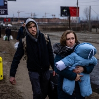 A family flees the city of Irpin, northwest of Kyiv, on Monday. | AFP-JIJI