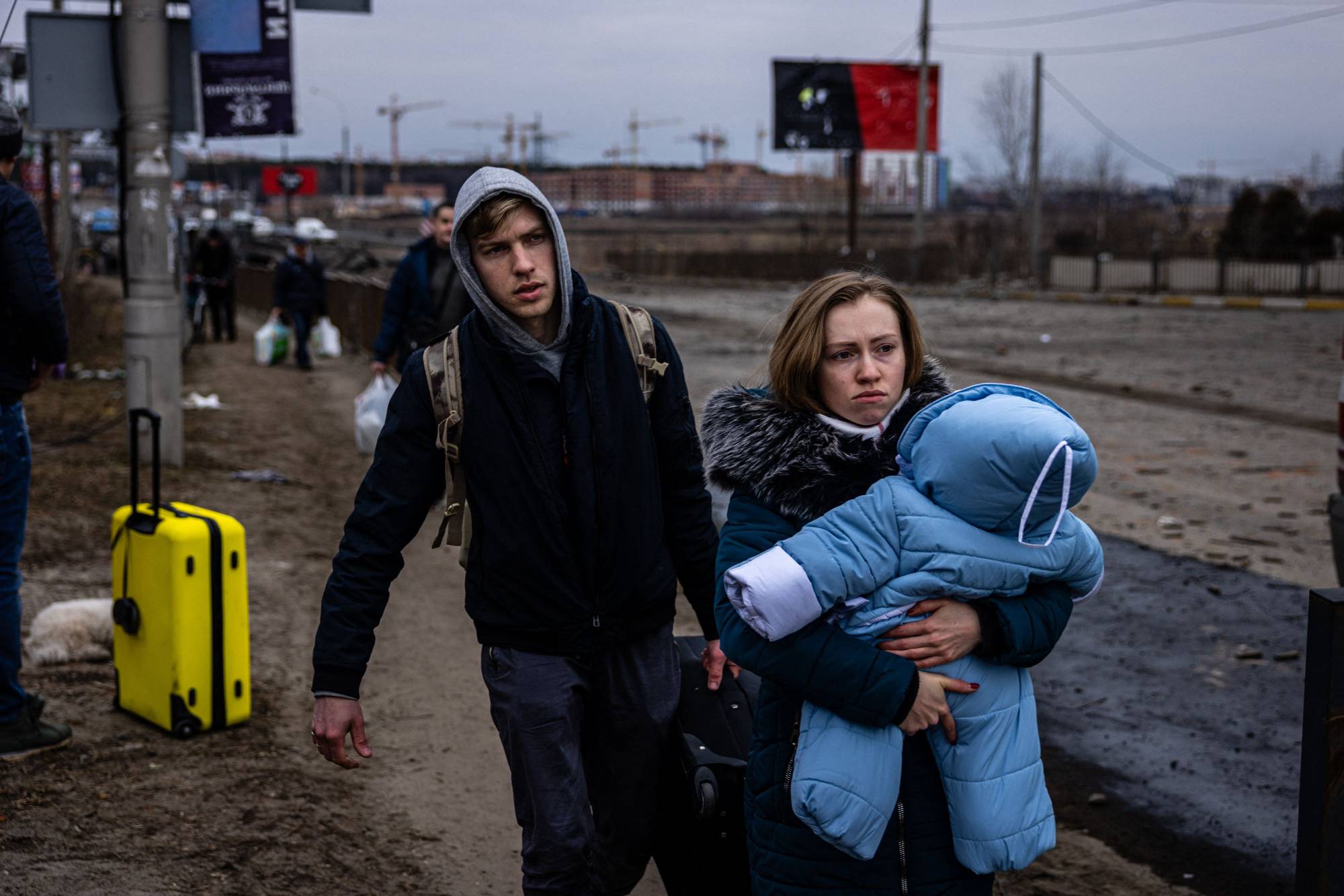 A family flees the city of Irpin, northwest of Kyiv, on Monday. | AFP-JIJI