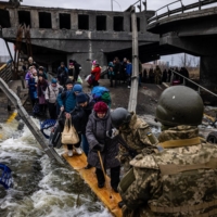 Evacuees cross a destroyed bridge as they flee the city of Irpin, northwest of Kyiv, on Monday. | AFP-JIJI