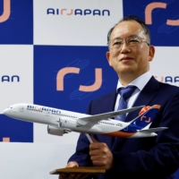 Hideki Mineguchi, president of ANA Holdings\' new carrier Air Japan, poses with its model plane after a news conference in Tokyo on Tuesday. | REUTERS