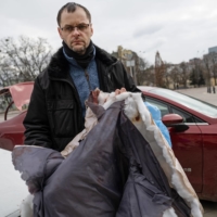 Serhiy Perebyinis holds the bloody coat that his wife, Tetiana wore as she and their children were killed by Russian mortar fire as they tried to evacuate, in Kyiv, on Wednesday.  | LYNSEY ADDARIO / THE NEW YORK TIMES



