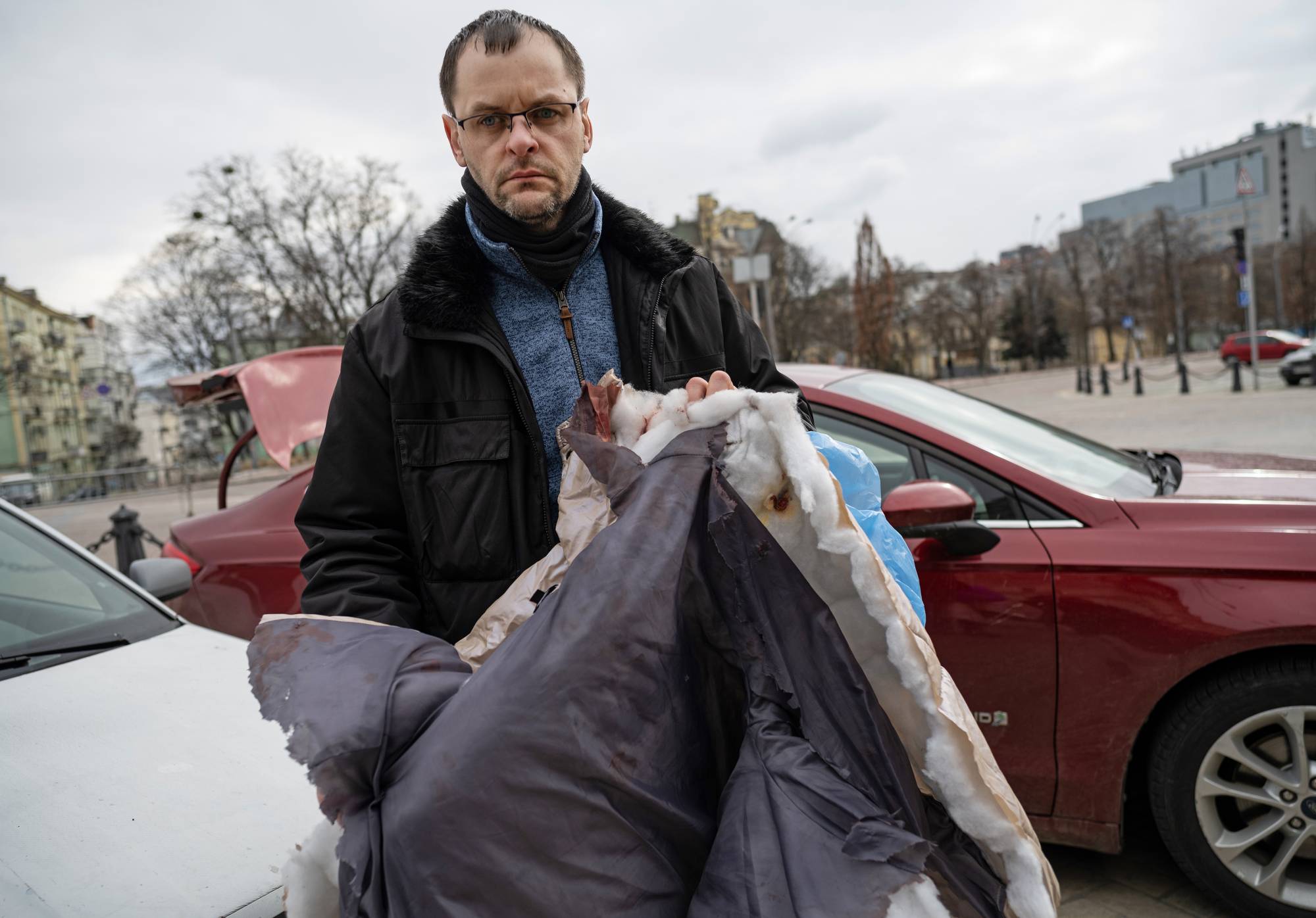 Serhiy Perebyinis holds the bloody coat that his wife, Tetiana wore as she and their children were killed by Russian mortar fire as they tried to evacuate, in Kyiv, on Wednesday. | Lynsey Addario / The New York Times 