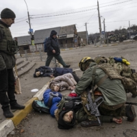 Moments after four civilians trying to evacuate were hit by Russian mortar fire, Ukrainian soldiers try to save Anatoly Berezhnyi — the only one who still had a pulse — in Irpin, west of Kyiv, on Sunday. Serhiy said he felt it was important the deaths of his wife and children had been recorded in photographs and video. \"The whole world should know what is happening here,\" he said. | LYNSEY ADDARIO / THE NEW YORK TIMES