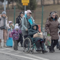 People arrive near a border checkpoint, after fleeing Russia\'s invasion of Ukraine, in Korczowa, Poland, on Thursday. | AGENCJA WYBORCZA.PL / VIA REUTERS