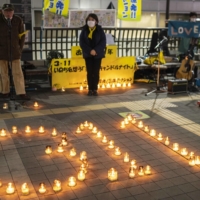 People take part in a candle vigil in memory of 2011 earthquake and tsunami victims in Mitaka, western Tokyo, on Friday.  | AFP-JIJI